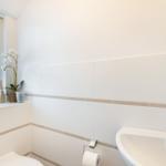 Bathroom with sink, toilet, and window with blinds.