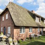 Red brick house with thatched roof and garden area with tables and chairs.