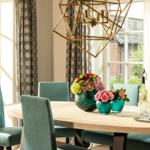 Esszimmer mit Holztisch, blauen Stühlen und Blumenvasen.