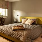 Schlafzimmer mit Bett, Fenster, Tisch und Stehlampe.