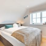 Schlafzimmer mit Doppelbett, Fenster und Nachttisch