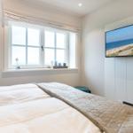 Schlafzimmer mit Bett, Fenster und Fernseher an der Wand.