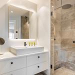 Badezimmer mit Waschtisch, Spiegel und Dusche mit Steinwand