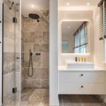 Dusche mit Steinwand und Waschbecken mit Spiegel