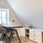 Arbeitsplatz mit Tisch, Stuhl und Schreibtischlampe unter Dachschrägenfenster.
