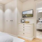 Schlafzimmer mit Kleiderschrank, TV und Blick in das Badezimmer.