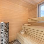 Sauna mit Holzbank, Steinofen und Fensterblick auf Strand