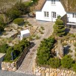 House with thatched roof, paved garden and stone path.