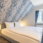 Bedroom with bed, wallpaper, and window with curtains.