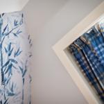Wall with bamboo pattern and blue checkered curtains at a window.