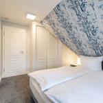 Bedroom with bed, wardrobe, and door. Wall with bamboo pattern.