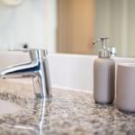 Sink with chrome faucet and soap dispenser on marble countertop.