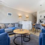 Living room with sofa, armchairs, and dining table. Kitchen with microwave and worktop.