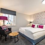 Bedroom with bed, armchair, and window. Wall with floral pattern.