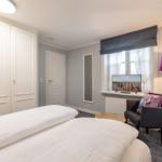 Bedroom with bed, wardrobe, armchair, and TV.