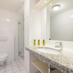 Bathroom with shower, toilet, and sink with mirror.
