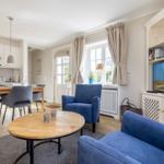 Living area with blue sofa, dining table, and kitchenette.