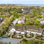 House with thatched roof and garden. View of the village and the lake.