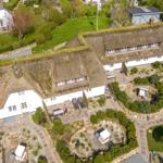 Farmhouse with thatched roof and landscaped garden area.