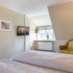 Bedroom with bed, TV, chair, and window.