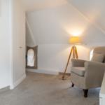 Attic room with armchair, floor lamp, and wardrobe.