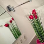 Mirror reflects red tulips in a pink vase.