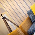 Sofa with cushions and floor lamp against striped wall