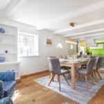 Dining room with wooden table, chairs, and view into kitchen