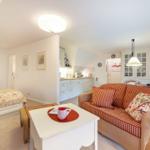 Living area with sofa, table, and bed. Kitchen in the background.
