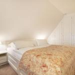 Bedroom with double bed, nightstand, and wardrobe under sloped ceiling.