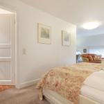 Bedroom with bed, door to bathroom, and view into living area.