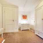 Bedroom with wardrobe, vanity table, and wall picture.