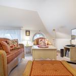 Living room with sofa, armchair, and TV under sloped ceiling