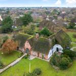 House with thatched roof, garden, and view of villages