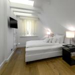 Schlafzimmer mit Dachbodenfenster, Bett, Nachttisch und Wand-TV.