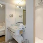 Badezimmer mit Dusche, Waschbecken und Blick in Schlafzimmer