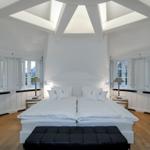 Schlafzimmer mit Doppelbett, weißen Fenstern und Holzboden.