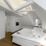 Schlafzimmer mit Dachschrägen, weißem Bett und Holzboden.