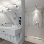 Moderne Dusche mit Glaswand und Waschbecken mit Spiegel.