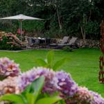 Garten mit Sonnenschirm, Sitzgruppe und Blumenbeeten.