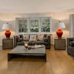 Wohnzimmer mit grauen Sofas, Holzboden und großen Fenstern.