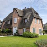 Haus mit Strohdach, weißem Eingang und Garten