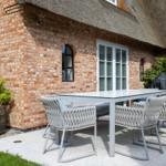 Terrasse mit Tisch und Stühlen vor Backsteinhaus mit Strohdach