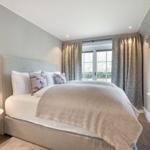 Schlafzimmer mit Bett, Vorhängen und Fenster zur Außenseite.