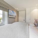 Schlafzimmer mit Bett, Fernseher und Fenster mit Blick auf Garten.