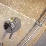 Duschbereich mit Chromarmatur und Handbrause an Steinwand