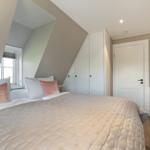 Schlafzimmer mit Dachschrägen, Bett, Kleiderschrank und Schminktisch.