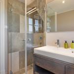 Badezimmer mit Dusche, Waschbecken und Spiegel.