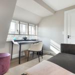 Zimmer mit Schreibtisch, Sofa und lila Sessel unter Dachschrägen.