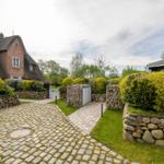 Haus mit Strohdach, Kiesweg und Steinmauern im Garten.